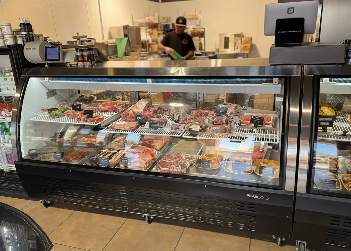 A Grinders butcher behind the full meat case